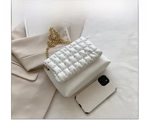 Detailed comparison of white quilted crossbody bag size alongside a smartphone
