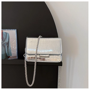 Detail view of silver crocodile embossed small square bag with metallic chain strap