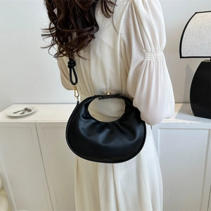 Sac à main demi-lune noir minimaliste avec détails dorés, porté par un mannequin élégant