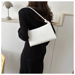 Détail du sac porté épaule blanc à motif crocodile et bandoulière nouée sur robe noire