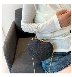 Detail of a black glitter heart bag with gold ring handle and elegant chain strap