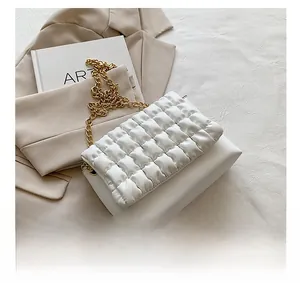 Detail of white quilted handbag with a chunky gold metal chain strap on a blazer