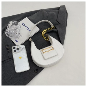 Détail du sac croissant blanc avec chaîne dorée et coutures texturées sur costume gris