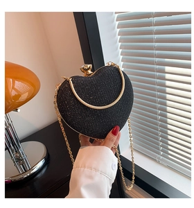 Detail of black heart-shaped evening bag with glitter texture and gold metal frame handle