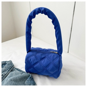 Detail of bright blue quilted handbag with diamond stitching and ruffled round handle