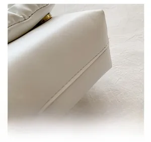 Close-up of precise white stitching and gold hardware on white leather crossbody bag