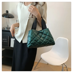 Détail d'un grand sac cabas matelassé vert brillant avec des larges poignées noires chic