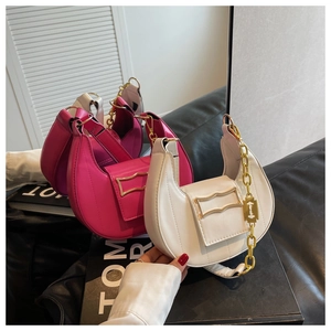 Détail de sacs croissants avec chaînes dorées et pendentifs en blanc et fuchsia