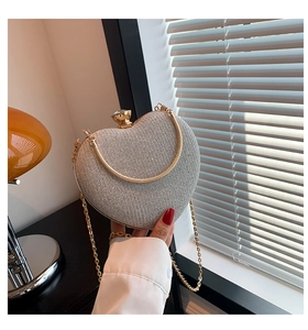 Close-up of heart-shaped clutch bag with silver glitter and crystal clasp held in hand