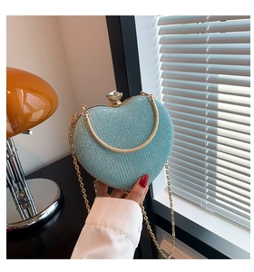 Close-up of light blue glitter heart-shaped evening bag with gold chain and gem knob