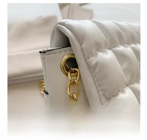 Close-up of white quilted leather bag with elegant gold chain hardware details
