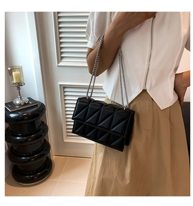 Detail of black geometric quilted crossbody bag with stylish silver metal chain strap