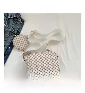 Detail of white printed crossbody bag with round coin purse and wide strap on denim