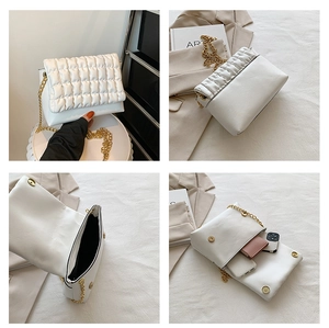 Detail view of white quilted bubble bag with gold chain strap and interior storage capacity