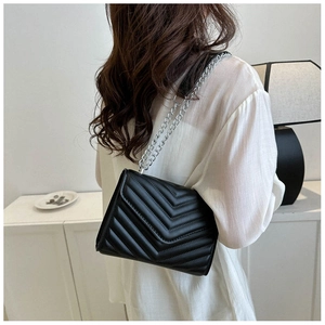 Detail of black chevron quilted shoulder bag with silver metal chain strap for women