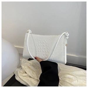 Détail d'un sac sous le bras blanc avec motif crocodile texturé et bandoulière à nœuds