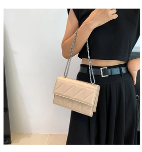 Detail of beige quilted shoulder bag featuring silver chain strap and 3D geometric pattern