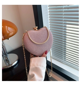 Macro view of light pink glitter heart-shaped bag with diamond clasp and gold chain
