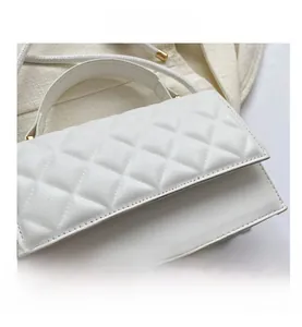 Makro-Detail der weißen gesteppten Handtasche mit Lederstruktur und goldenen Beschlägen