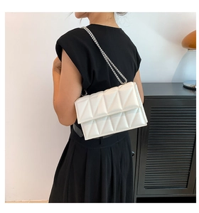 White geometric quilted chain bag shown on a model for size and style reference