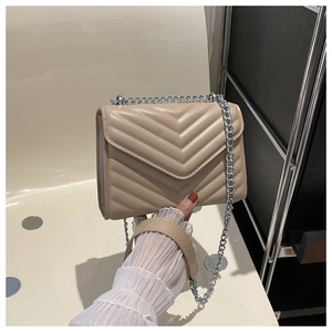 Detail of beige chevron stitched crossbody bag with elegant silver chain strap handle