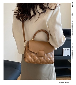 Détail d'un sac bandoulière matelassé marron avec poignée tressée et accents dorés sur un mannequin