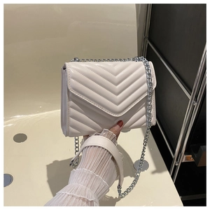 Close-up of beige quilted crossbody bag with silver chain strap and envelope flap design