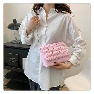 Detail of pink pleated texture on crossbody bag with elegant gold chain strap
