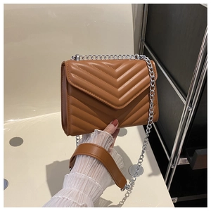 Detail of caramel quilted leather shoulder bag with V-shaped stitching and silver chain strap