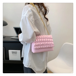 Close-up of pink pleated texture crossbody bag with elegant gold metal chain strap