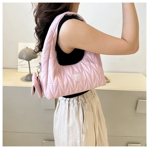 Sac à bandoulière matelassé rose avec mini pochette amovible porté par un mannequin