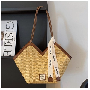Detail of hand-woven straw tote with brown leather straps and chic logo ribbon