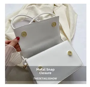 Detailaufnahme der weißen Ledertasche mit zwei goldenen Magnetverschlüssen aus Metall
