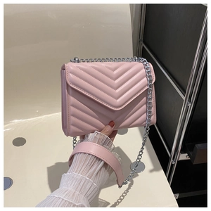 Close-up of pink quilted crossbody bag with V-shaped stitching and silver chain strap