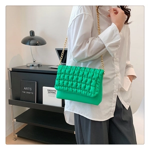 Detailed view of bright green puffy quilted shoulder bag with elegant gold chain strap