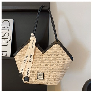 Detail of a woven straw tote bag with black faux leather handles and smile patch