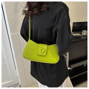 Detail of lime green baguette bag with circular ring buckle worn over a black outfit