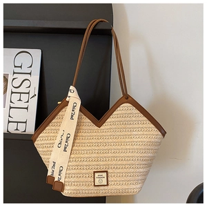 Close-up of beige straw tote bag featuring brown leather trim and V-shaped opening detail