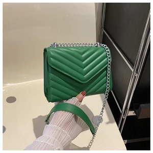 Detailed view of green quilted chain shoulder bag with V-shaped stitching and silver chain