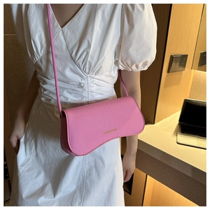 Detail of bright pink crossbody bag with crocodile texture and fashion logo lettering