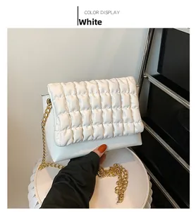Macro shot of white quilted bubble bag fabric with premium gold metal chain detail