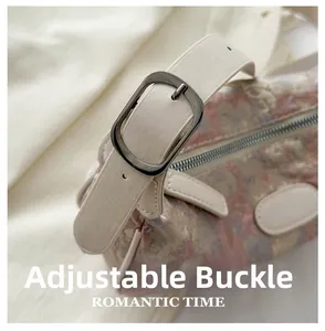 Macro detail of the adjustable silver buckle and floral embroidery on the pink dumpling bag
