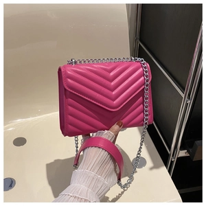 Close-up of rose red V-shaped chevron quilted crossbody bag with silver chain strap
