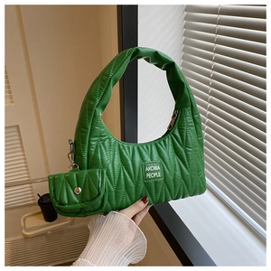 Détail du sac matelassé vert avec texture rembourrée et charm porte-monnaie assorti sur le côté