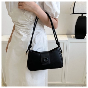 Chic black minimalist shoulder bag with knotted strap and round buckle detail on model
