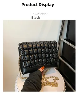 Detail of black puffy quilted handbag featuring gold metal chain strap on display