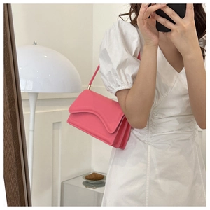 Detail view of pink leather underarm bag with accordion fold design and slim shoulder strap