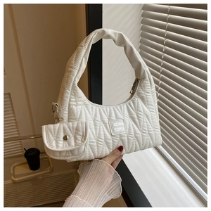 Détail d'un sac à bandoulière matelassé blanc avec mini pochette amovible et étiquette