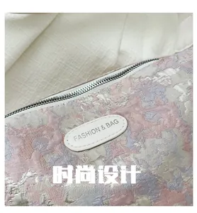 Macro detail of pink floral jacquard fabric and silver zipper on the dumpling bag