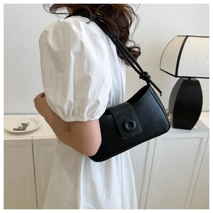 Detail of minimalist black leather shoulder bag with knot strap and round button closure